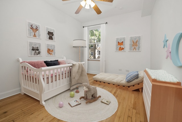 bedroom featuring vaulted ceiling, ceiling fan, hardwood / wood-style floors, and a crib