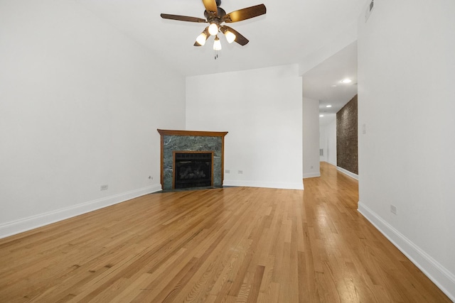 unfurnished living room featuring ceiling fan, light hardwood / wood-style floors, and a high end fireplace