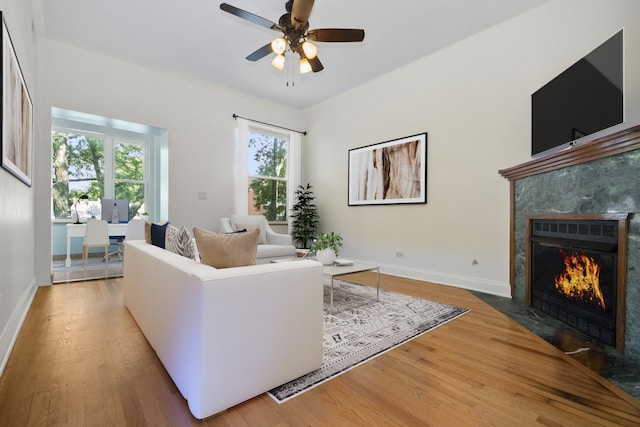 living room with ceiling fan, hardwood / wood-style floors, and a high end fireplace