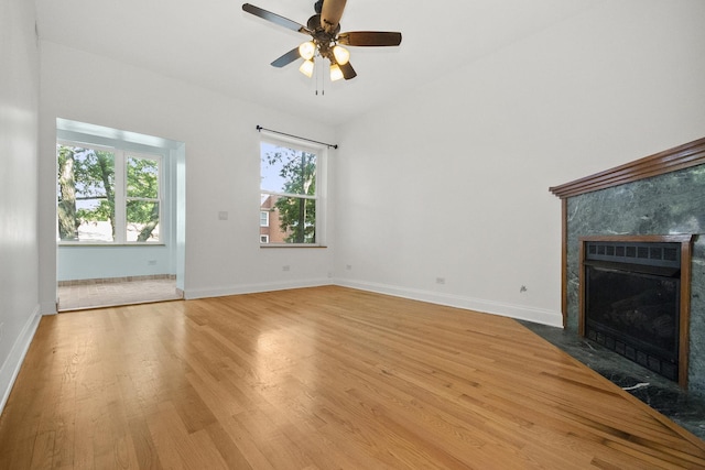 unfurnished living room with hardwood / wood-style flooring, ceiling fan, and a premium fireplace