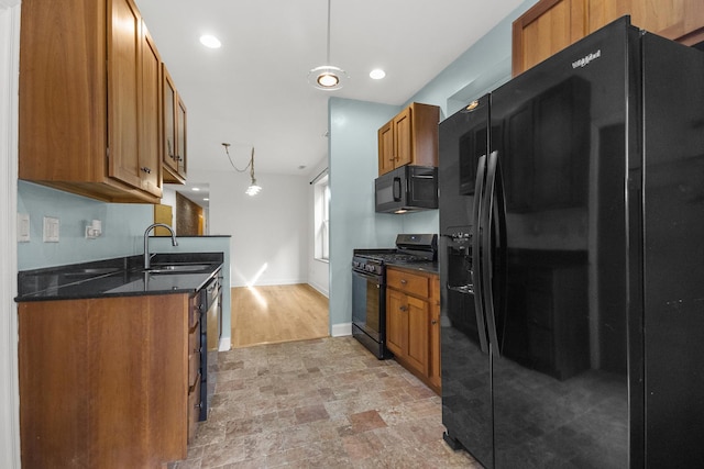 kitchen with black appliances, decorative light fixtures, dark stone countertops, and sink