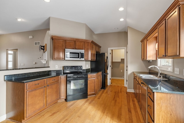 kitchen featuring dark stone counters, black appliances, sink, vaulted ceiling, and light hardwood / wood-style flooring