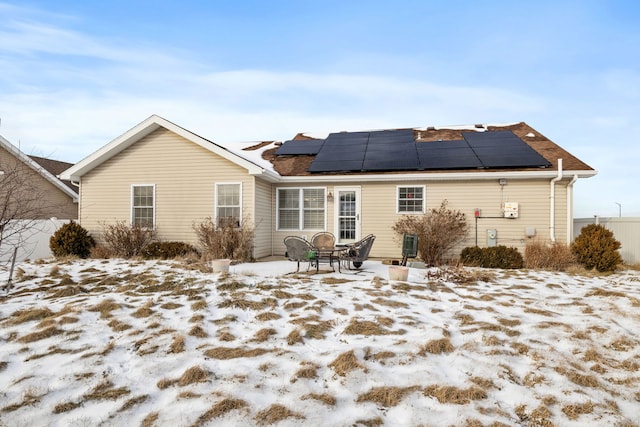 snow covered back of property with solar panels