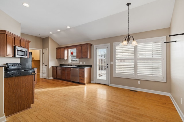 kitchen featuring light hardwood / wood-style flooring, vaulted ceiling, appliances with stainless steel finishes, decorative light fixtures, and a chandelier