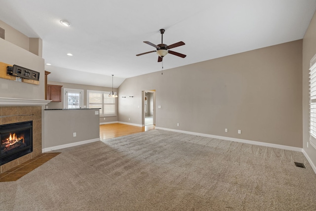 unfurnished living room featuring a fireplace, light colored carpet, ceiling fan, and lofted ceiling