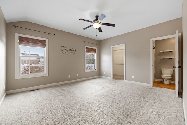 unfurnished bedroom with ensuite bath, a spacious closet, ceiling fan, vaulted ceiling, and a closet