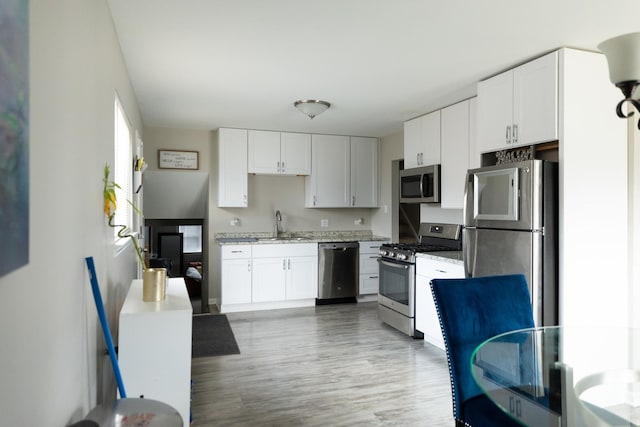 kitchen with sink, white cabinets, light hardwood / wood-style flooring, and appliances with stainless steel finishes