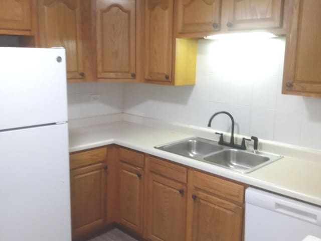 kitchen with backsplash, white appliances, and sink