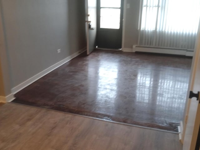 spare room with dark hardwood / wood-style flooring and a baseboard heating unit