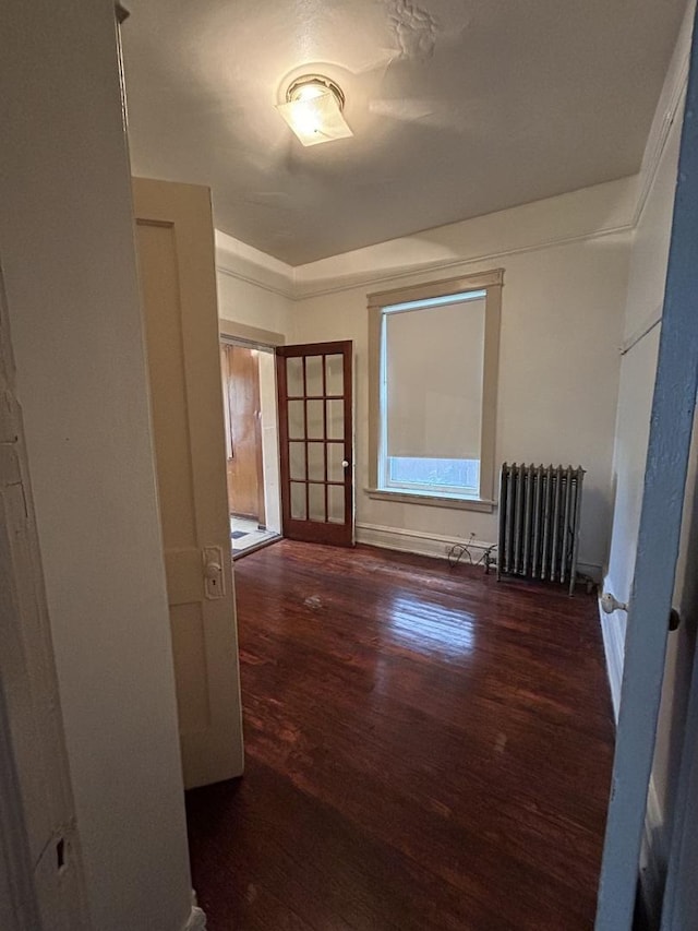 spare room featuring radiator and dark wood-type flooring