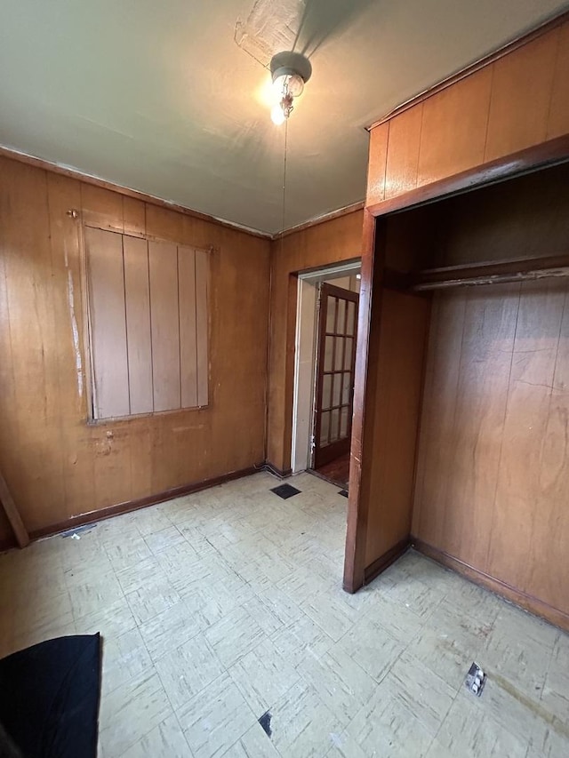 unfurnished bedroom featuring a closet and wooden walls