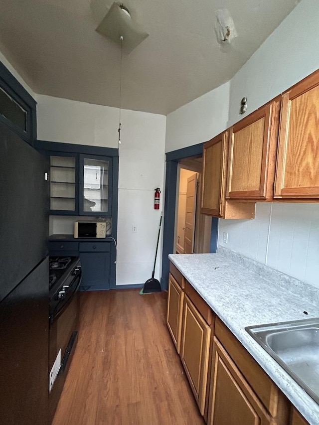 kitchen featuring black appliances, wood-type flooring, and sink