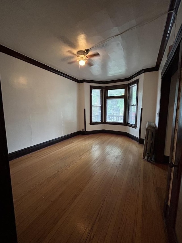 spare room with ceiling fan, ornamental molding, radiator heating unit, and light hardwood / wood-style flooring