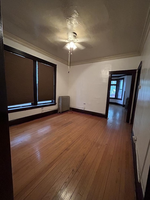 spare room featuring radiator, ornamental molding, a textured ceiling, ceiling fan, and wood-type flooring