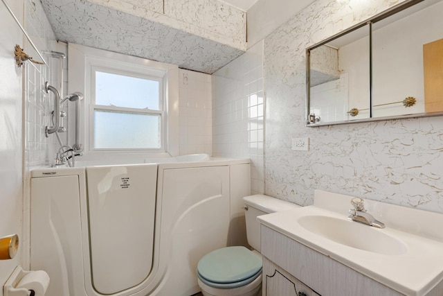 bathroom with a tub, vanity, and toilet