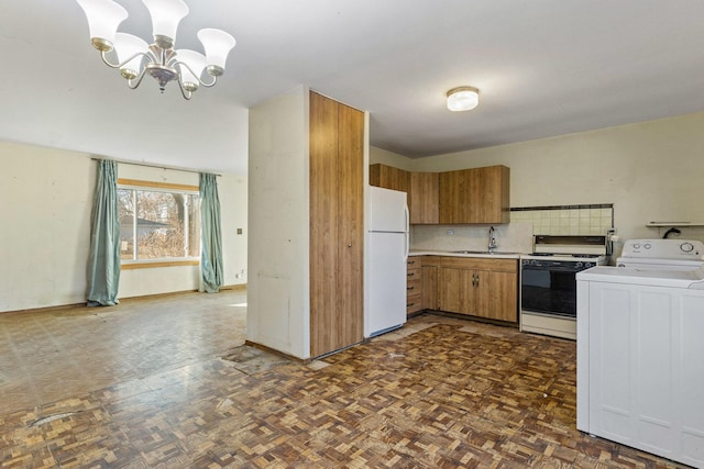 kitchen featuring dark parquet flooring, white appliances, sink, a chandelier, and washer / clothes dryer