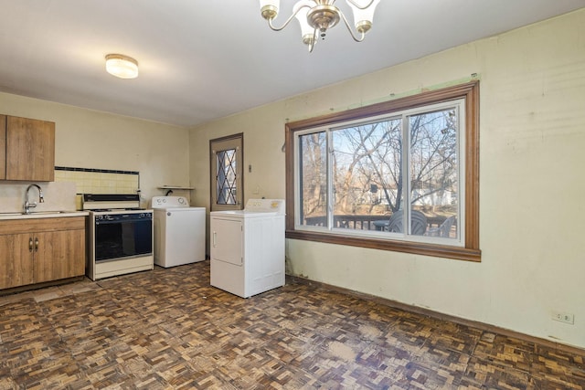 laundry room with dark parquet floors, an inviting chandelier, washer and clothes dryer, and sink