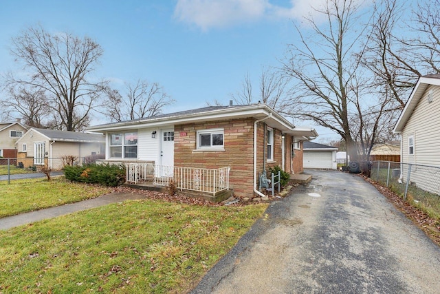 view of front of house with an outbuilding, fence, a garage, stone siding, and a front lawn