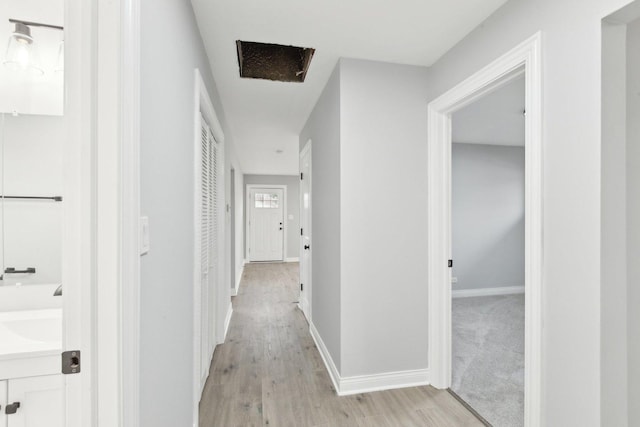 corridor with light wood-style flooring and baseboards