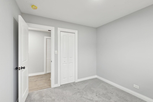 unfurnished bedroom featuring carpet, baseboards, and a closet