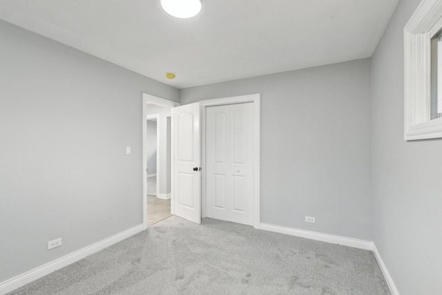 unfurnished bedroom with carpet floors, baseboards, and a closet