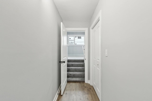 hall featuring light wood-style flooring and baseboards