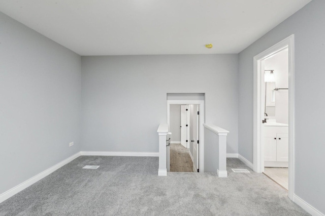 unfurnished room with carpet floors, baseboards, and a sink