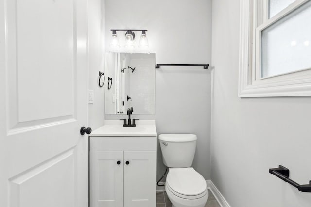 bathroom featuring walk in shower, vanity, toilet, and baseboards