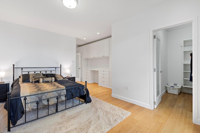 bedroom with light hardwood / wood-style flooring and a spacious closet