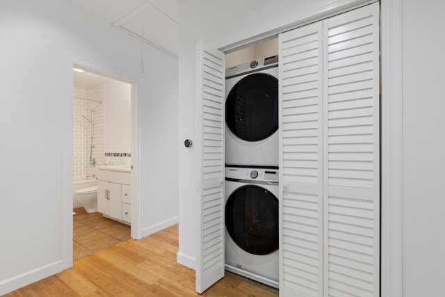 laundry area featuring stacked washing maching and dryer and light wood-type flooring