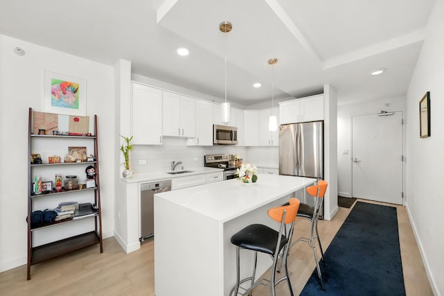 kitchen featuring sink, pendant lighting, a breakfast bar area, a kitchen island, and appliances with stainless steel finishes