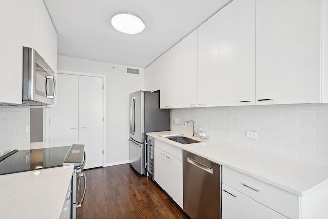 kitchen featuring sink, white cabinetry, appliances with stainless steel finishes, dark hardwood / wood-style floors, and light stone countertops