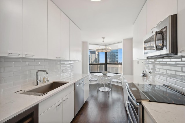 kitchen featuring white cabinetry, sink, stainless steel appliances, and hanging light fixtures