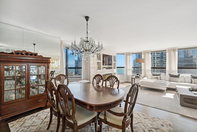 dining area featuring a notable chandelier, a water view, and light wood-type flooring