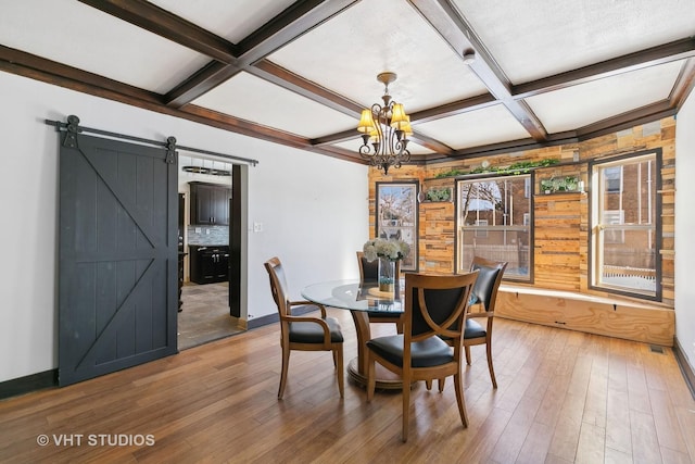 dining area with coffered ceiling, beam ceiling, an inviting chandelier, a barn door, and hardwood / wood-style floors