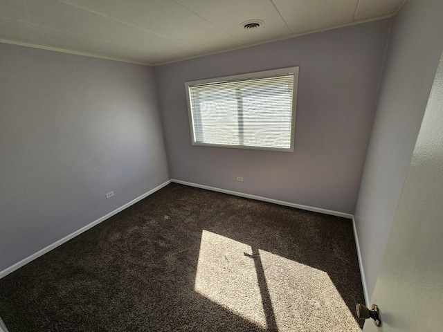 empty room featuring dark carpet and ornamental molding