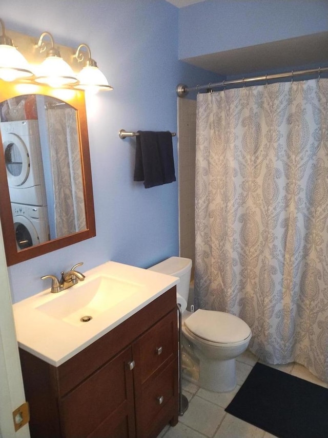 bathroom featuring vanity, tile patterned flooring, a shower with shower curtain, toilet, and stacked washing maching and dryer