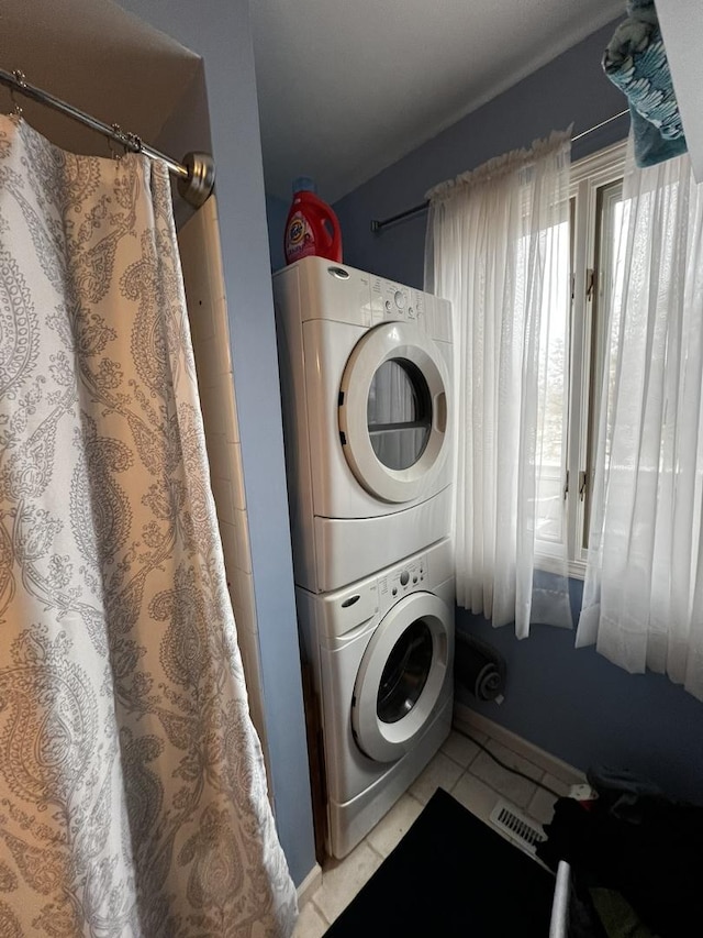 laundry room featuring light tile patterned flooring and stacked washing maching and dryer