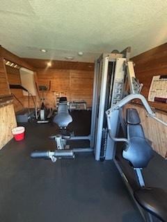 workout area featuring wood walls and a textured ceiling