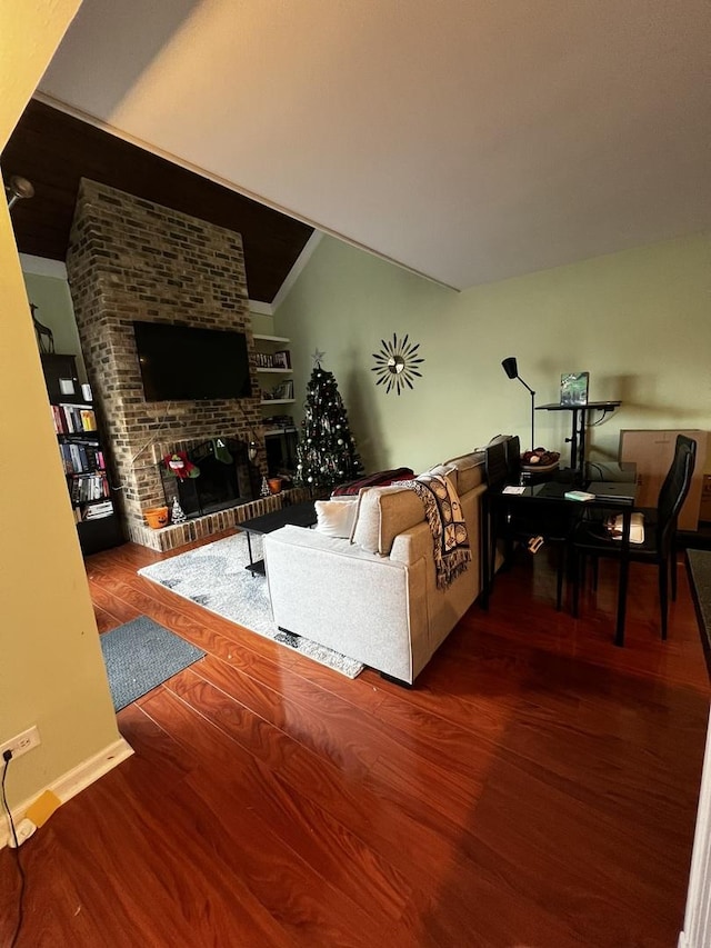 living room with a fireplace, hardwood / wood-style flooring, and vaulted ceiling