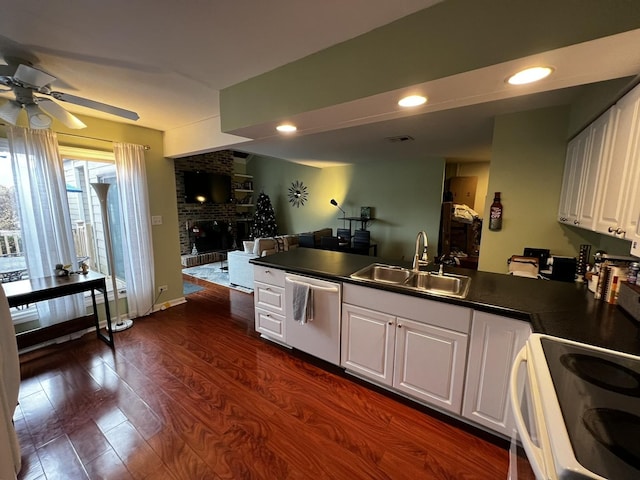 kitchen featuring dishwasher, sink, a brick fireplace, dark hardwood / wood-style flooring, and white cabinets