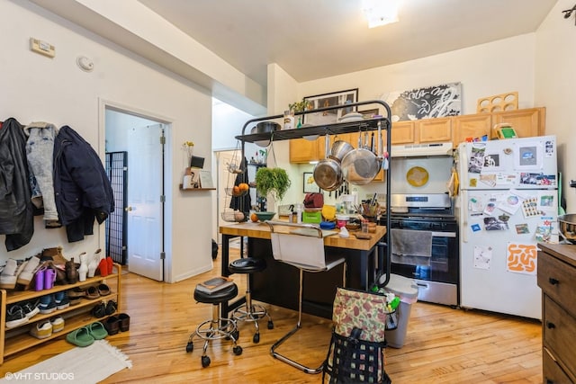 kitchen with stainless steel range, light hardwood / wood-style floors, and white refrigerator