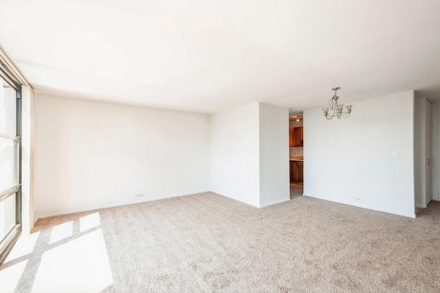 carpeted empty room with an inviting chandelier