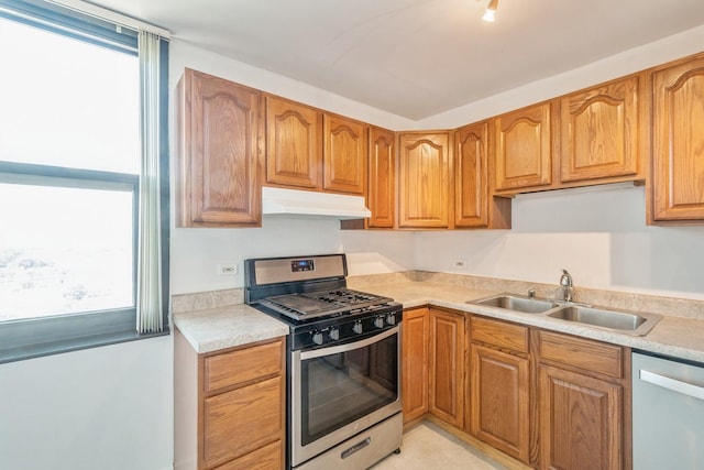 kitchen with a wealth of natural light, sink, light tile patterned floors, and stainless steel appliances