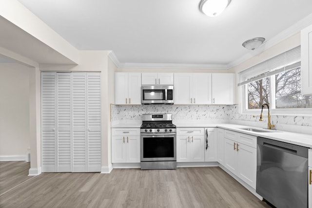 kitchen featuring decorative backsplash, white cabinetry, sink, and appliances with stainless steel finishes