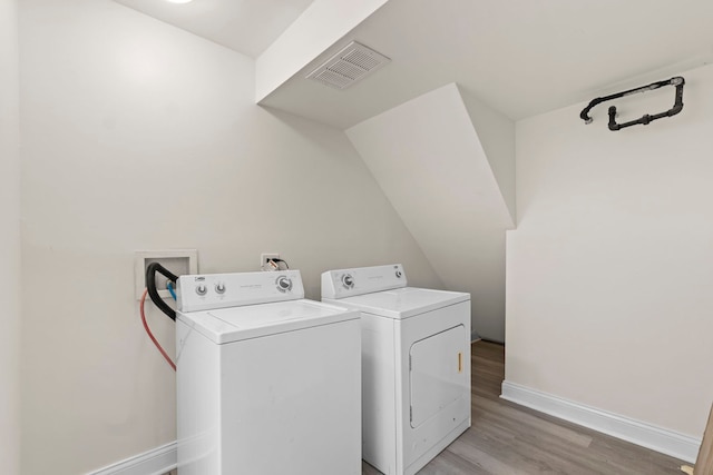 clothes washing area featuring independent washer and dryer and light hardwood / wood-style floors