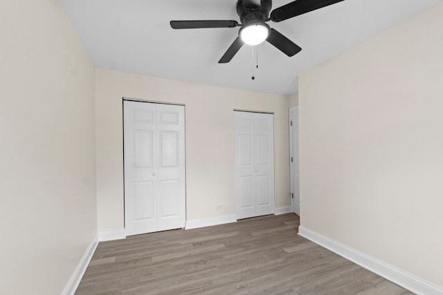 unfurnished bedroom with ceiling fan, light hardwood / wood-style flooring, and multiple closets