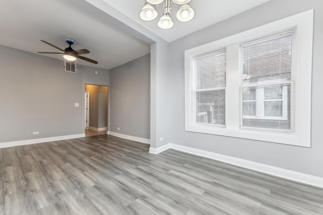 empty room featuring light hardwood / wood-style flooring and ceiling fan with notable chandelier