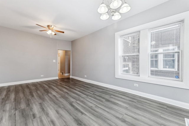 spare room with wood-type flooring, ceiling fan with notable chandelier, and a wealth of natural light