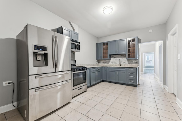 kitchen featuring backsplash, gray cabinetry, stainless steel appliances, sink, and light tile patterned flooring